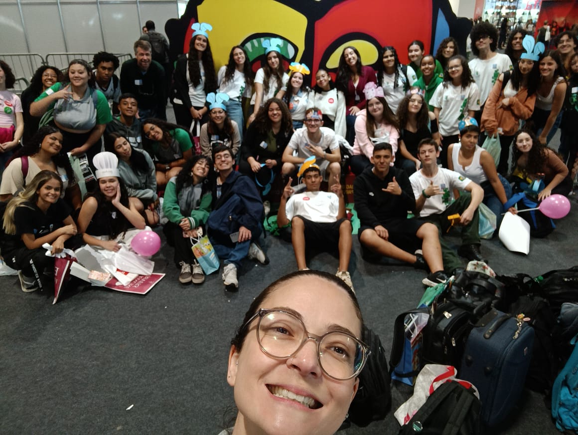 Thaís faz selfie com grupo de estudantes durante passeio. Créditos da imagem: acervo pessoal da servidora